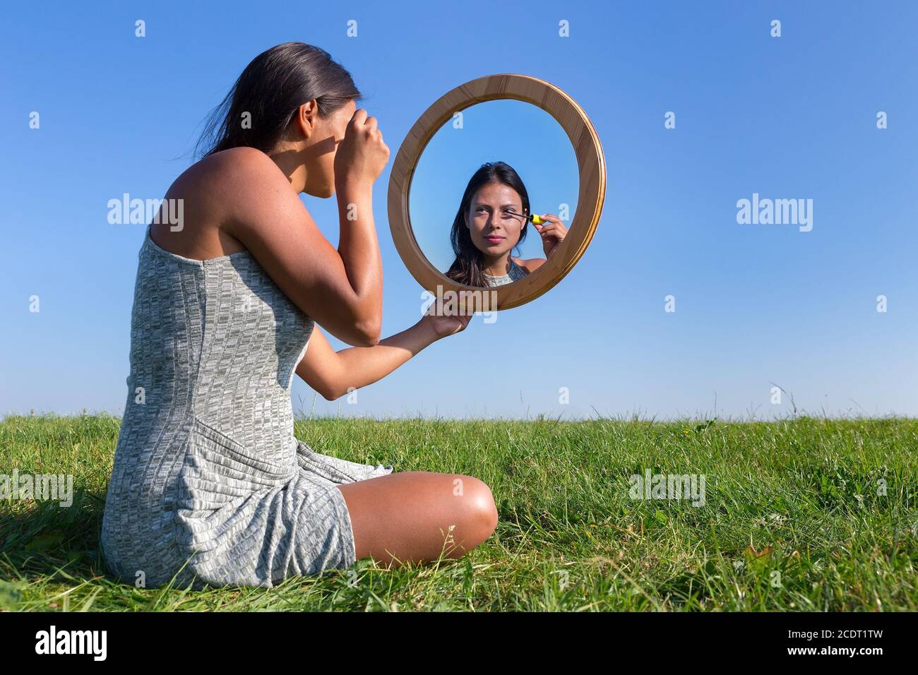 Donna che applica trucco cosmetico mascara nello specchio esterno Foto Stock