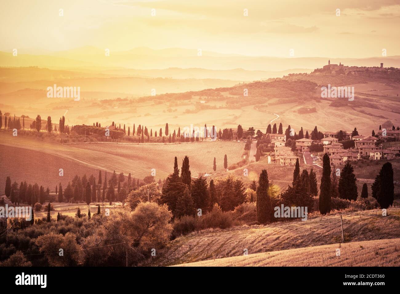 Meraviglioso paesaggio toscano con cipressi, fattorie e piccoli borghi medievali, Italia. Tramonto d'epoca Foto Stock