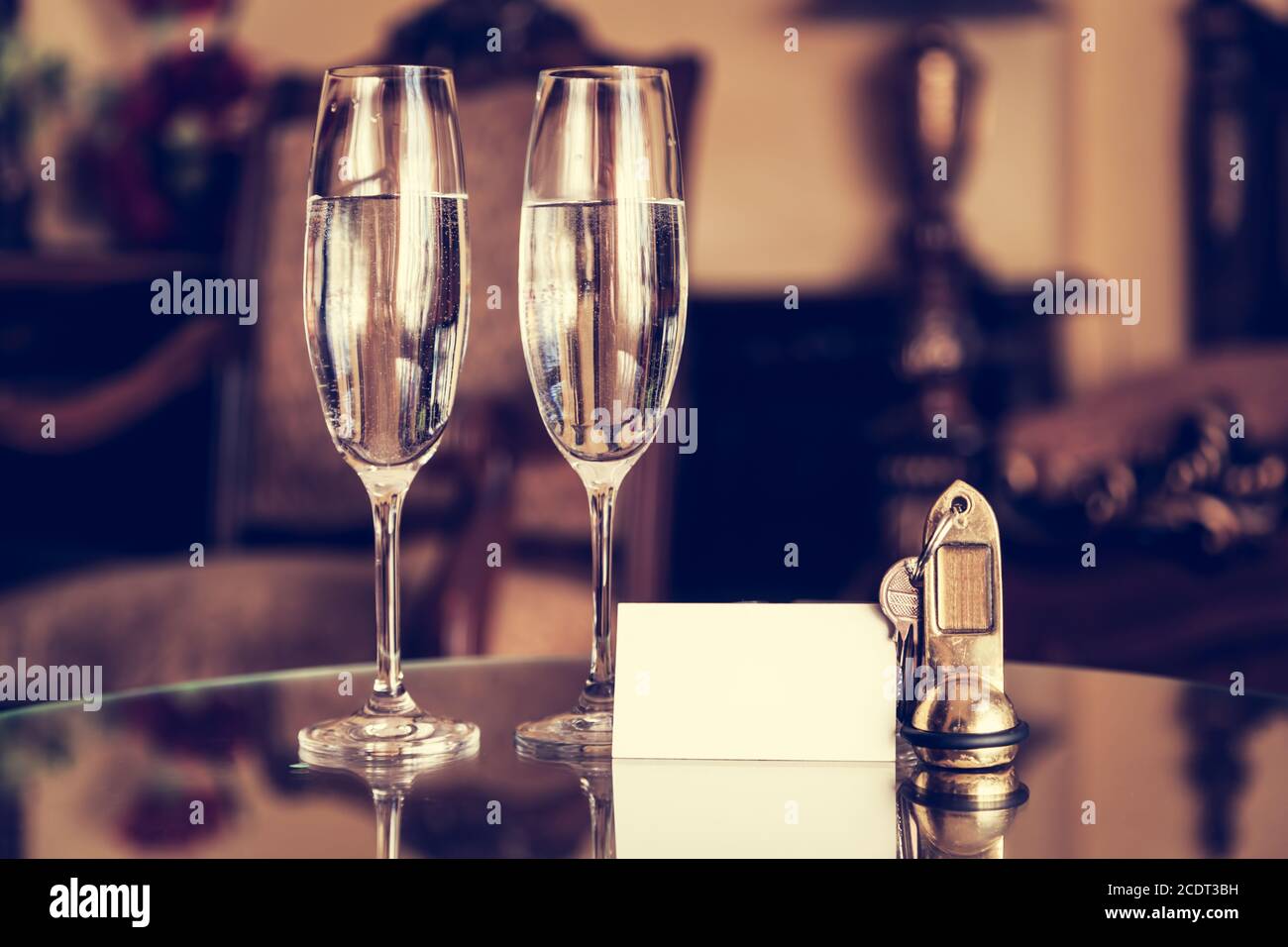Bicchieri completi di champagne, chiavi antiche e tessera bianca vuota. Appartamento di lusso Foto Stock