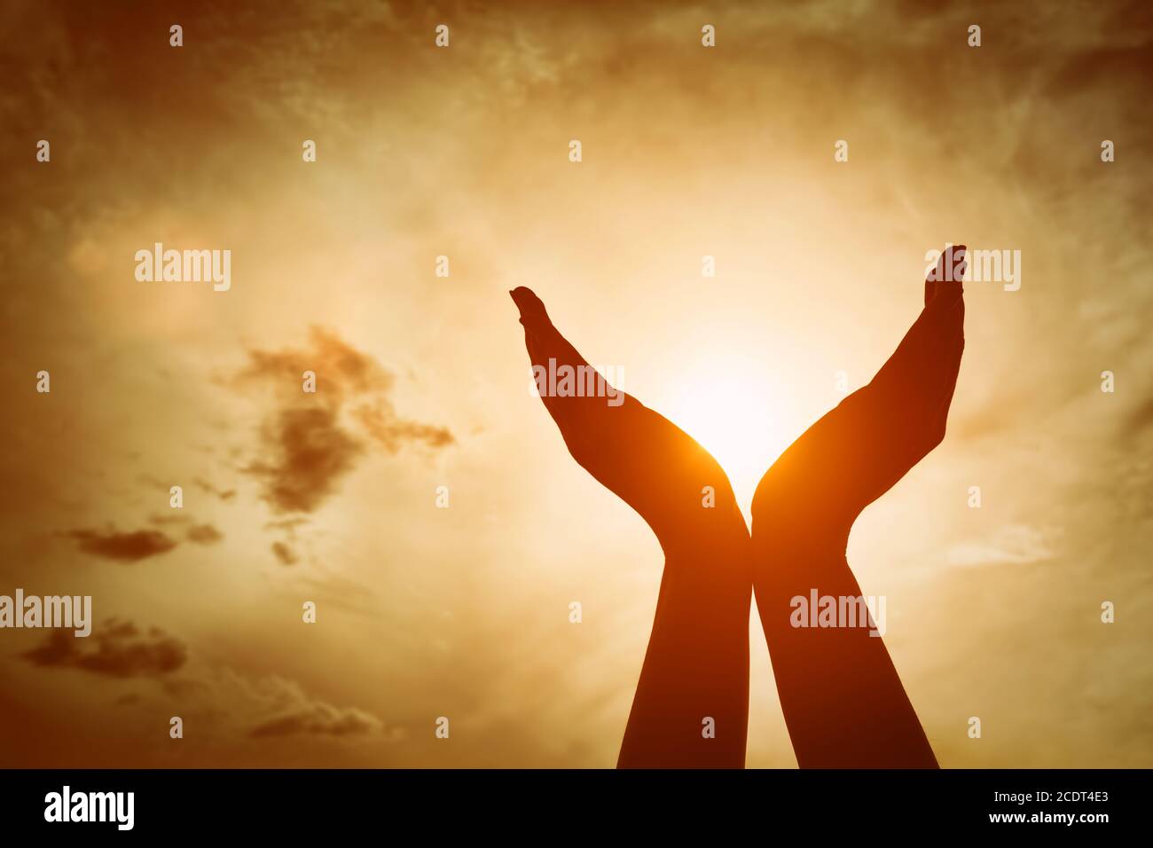 Mani alzate che catturano il sole sul cielo del tramonto. Concetto di spiritualità, benessere, energia positiva Foto Stock