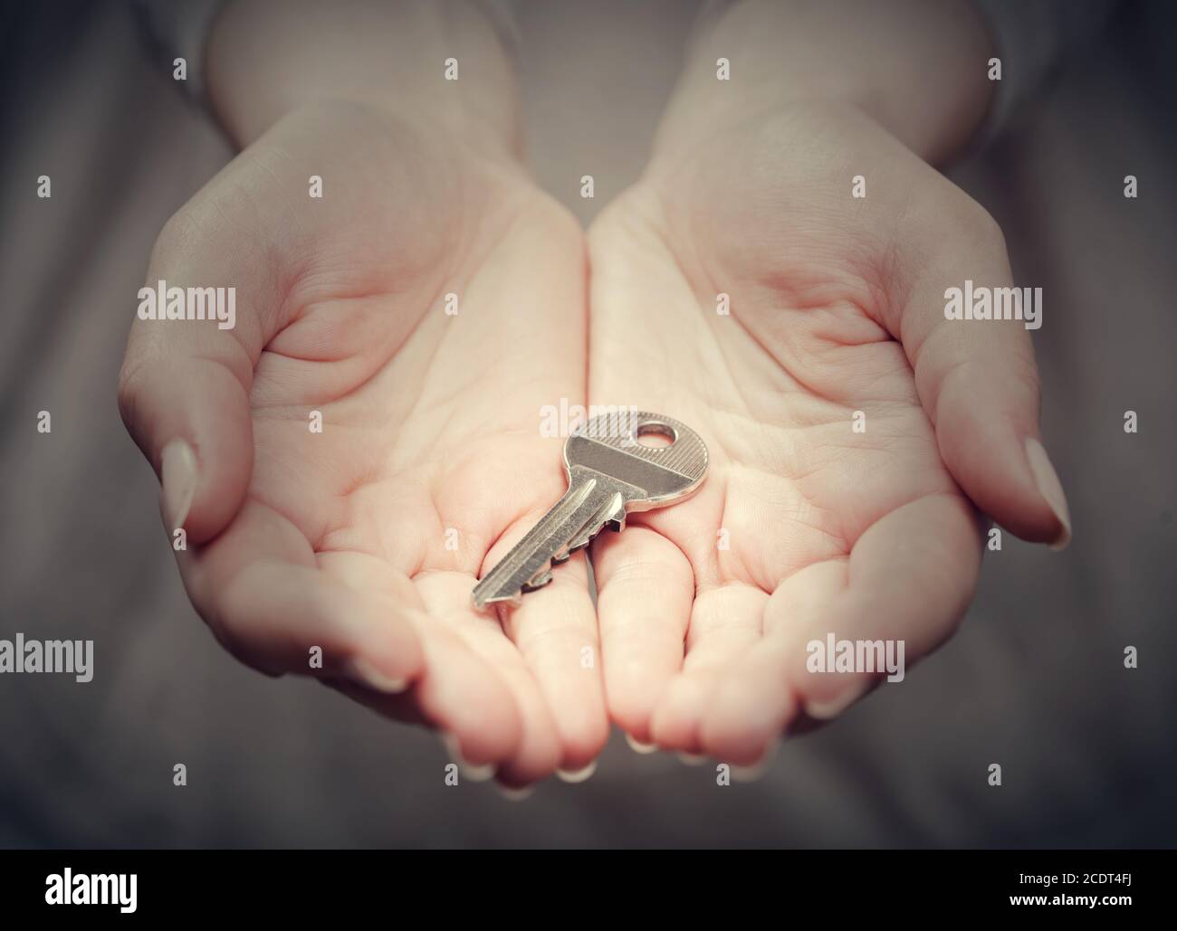 La chiave nella mano della donna n° 39;s nel gesto di dare. Concetto di successo in live, soluzione aziendale, immobiliare, ecc. Foto Stock