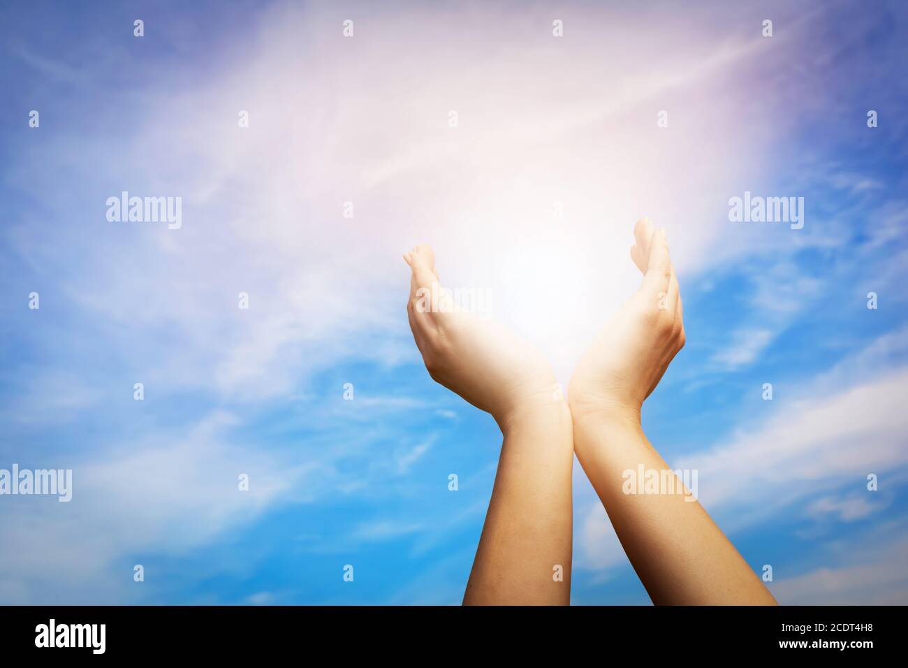 Mani alzate che catturano il sole sul cielo blu. Concetto di spiritualità, benessere, energia positiva Foto Stock