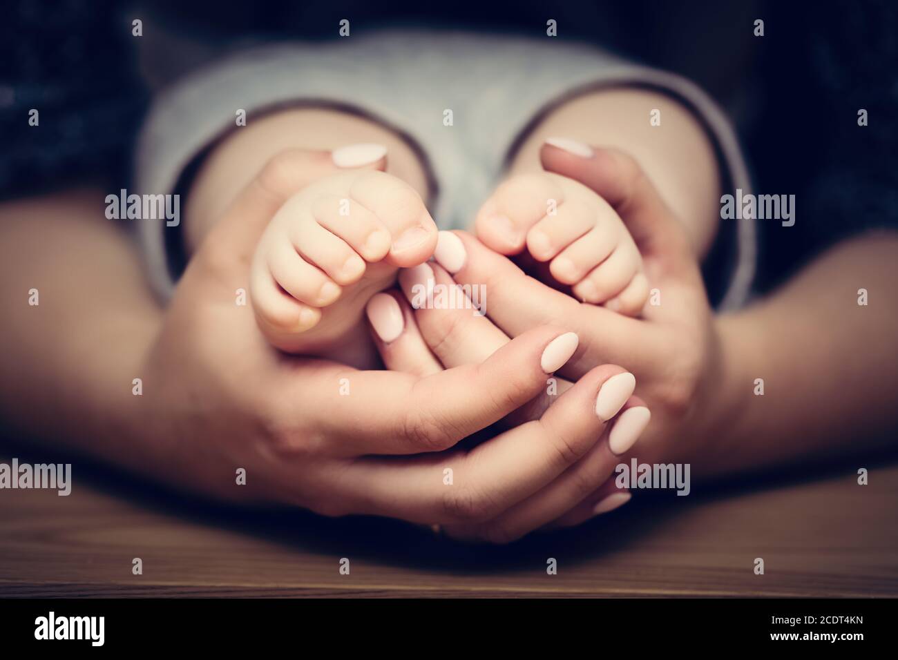 I piedi piccoli del bambino nelle mani della madre. Cura dei bambini, sentirsi sicuri, proteggere. Foto Stock