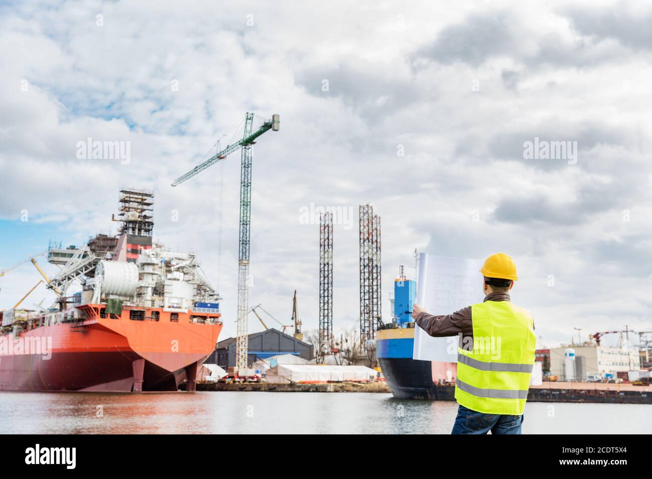 Ingegnere cantieristico che controlla i documenti sul lato della banchina in un porto. Foto Stock