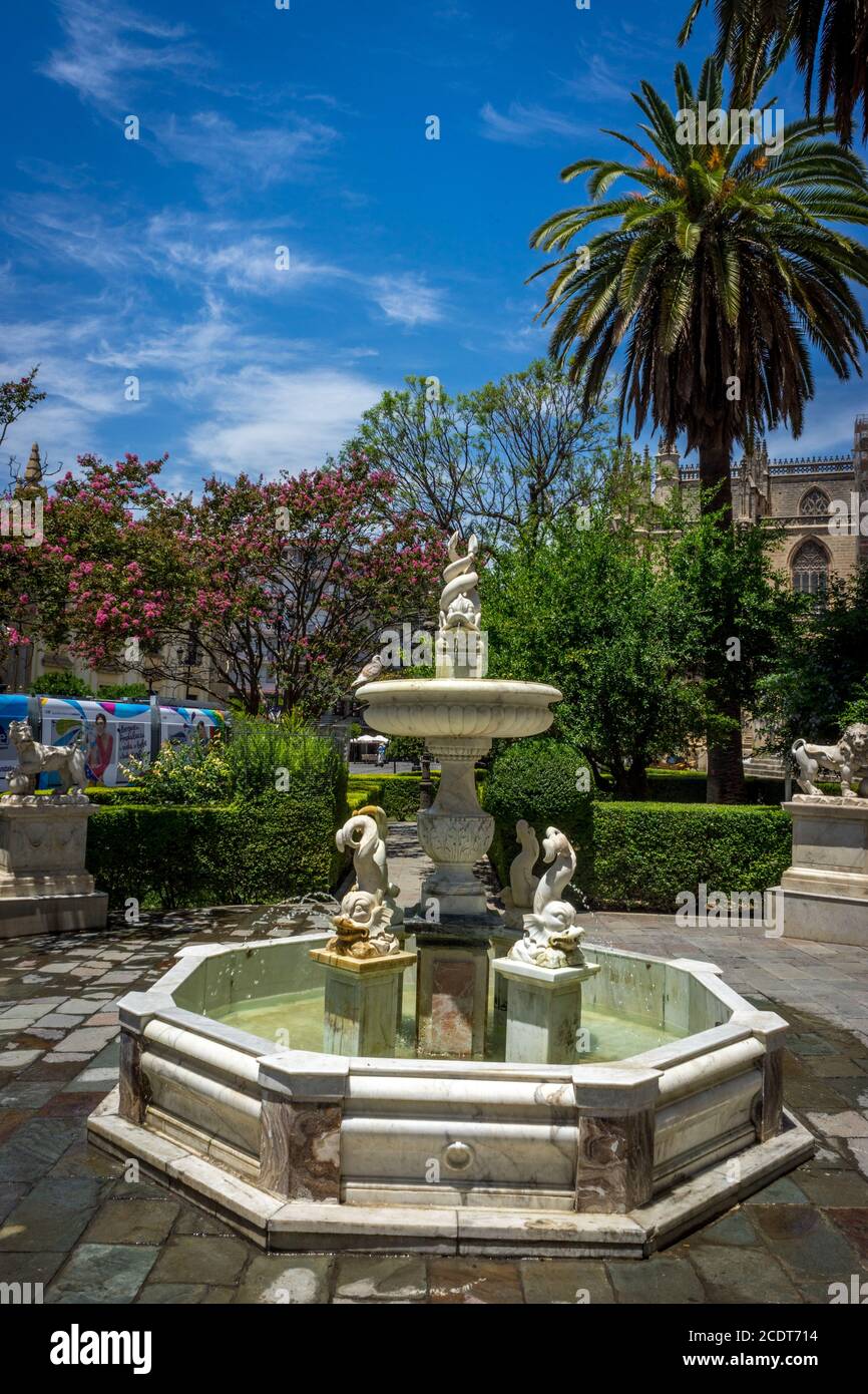 Fontana d'acqua con palme sullo sfondo in una giornata luminosa e soleggiata con cielo blu a Siviglia, Spagna, Europa. Foto Stock