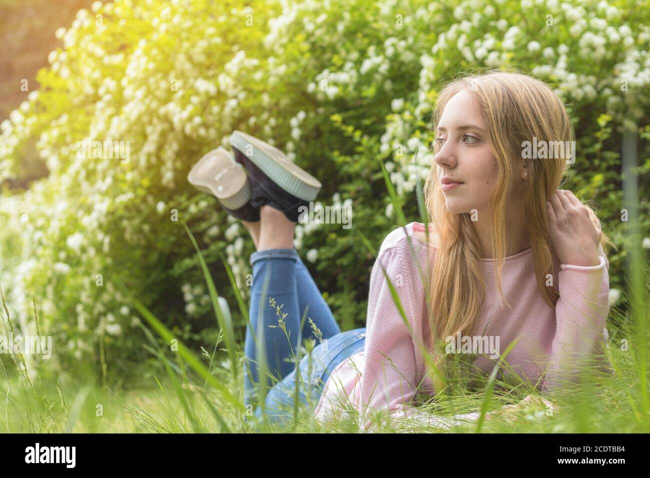 Bella ragazza-adolescente bionda sognare in una giornata di sole sul erba Foto Stock