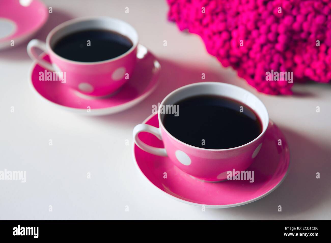 Due tazze da caffè rosa su sfondo bianco, pausa caffè e aggiunta di caffeina concetto. Fiori gialli sul tavolo Foto Stock