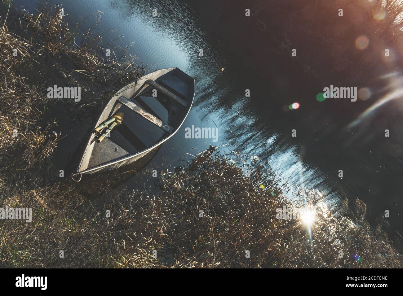 La barca di legno pacificamente in appoggio sull'acqua del fiume autunno al tramonto Foto Stock