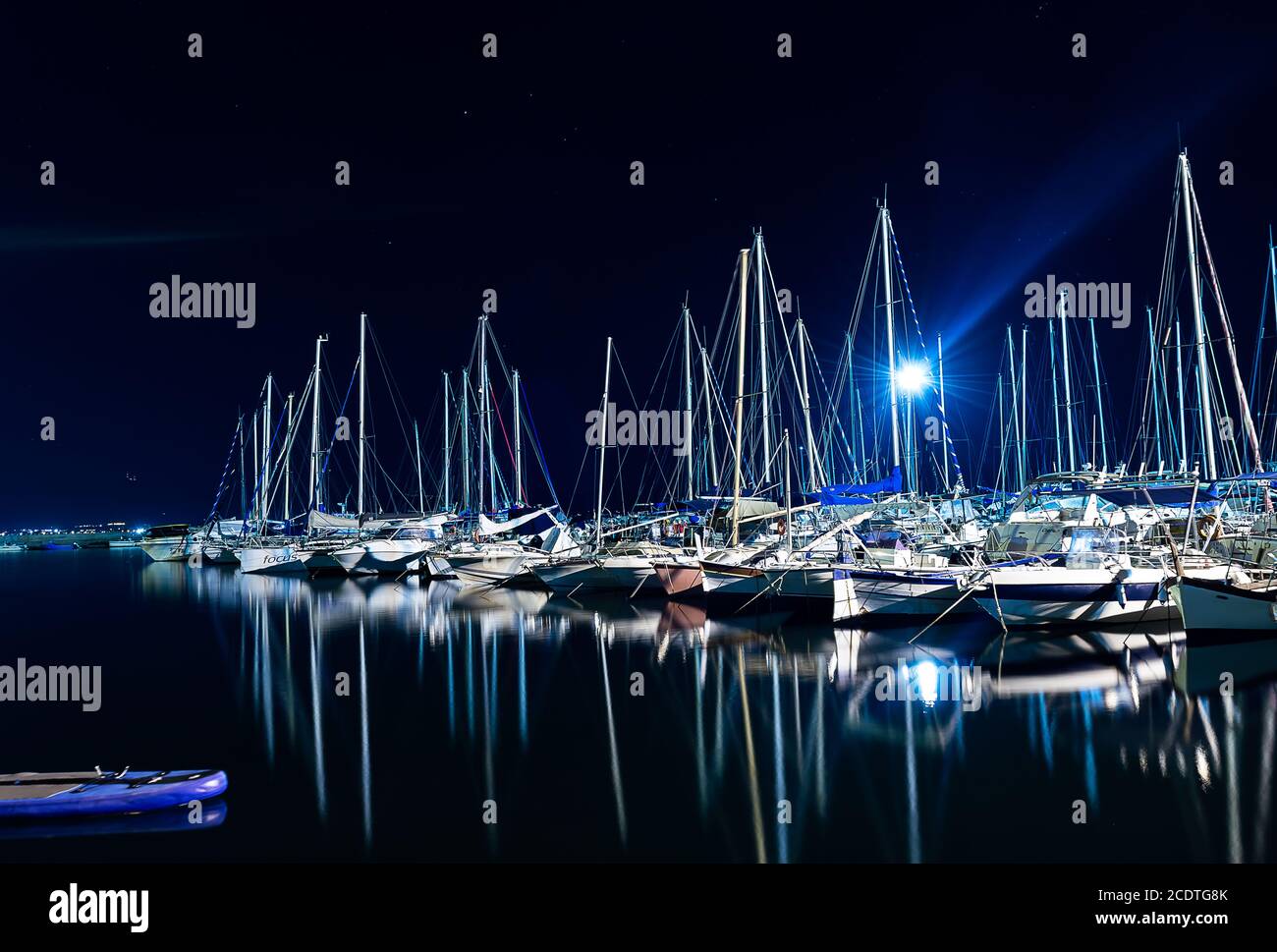 molte barche ormeggiate in un molo della città di notte Foto Stock