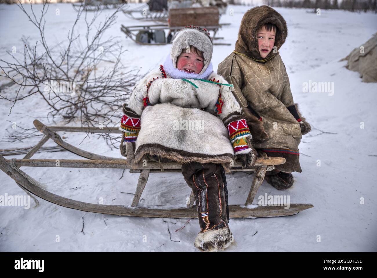 Giovane Nenet ragazza e ragazzo seduto su una slitta con abiti tradizionali, Yamalo-Nenets Autonomous Okrug, Russia Foto Stock