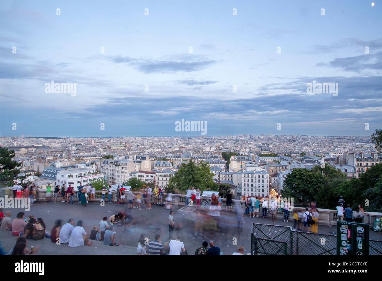 Parigi, Francia. 2019, agosto. Tramonto su Parigi da Montmartre alla basilica del Sacro cuore e persone sedute sulle scale in una giornata estiva nuvolosa. Tetti Foto Stock