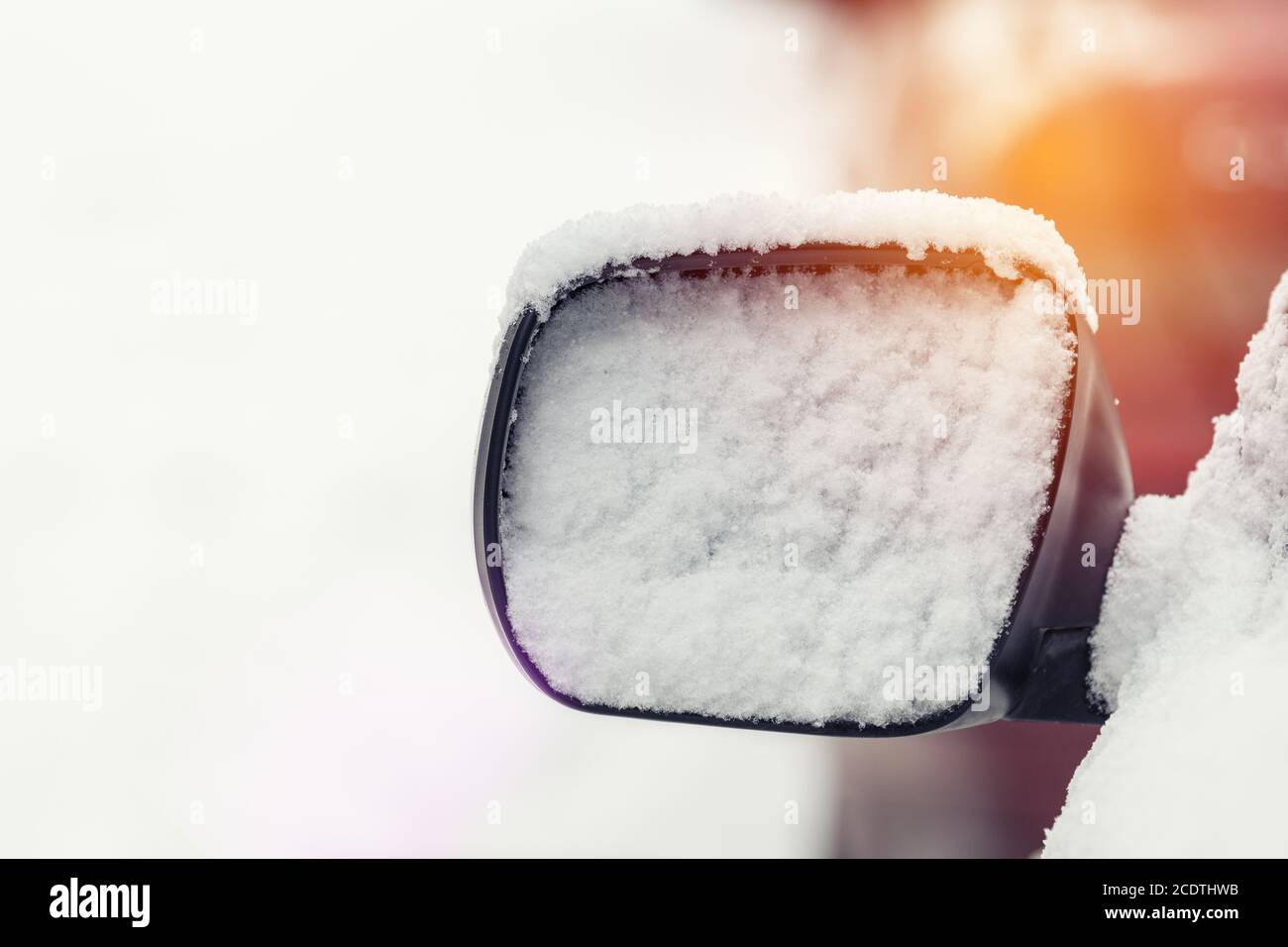 L'auto è coperta di neve. Neve sullo specchietto retrovisore. Concetto di guida in inverno con neve su strada. Foto a colori con Foto Stock