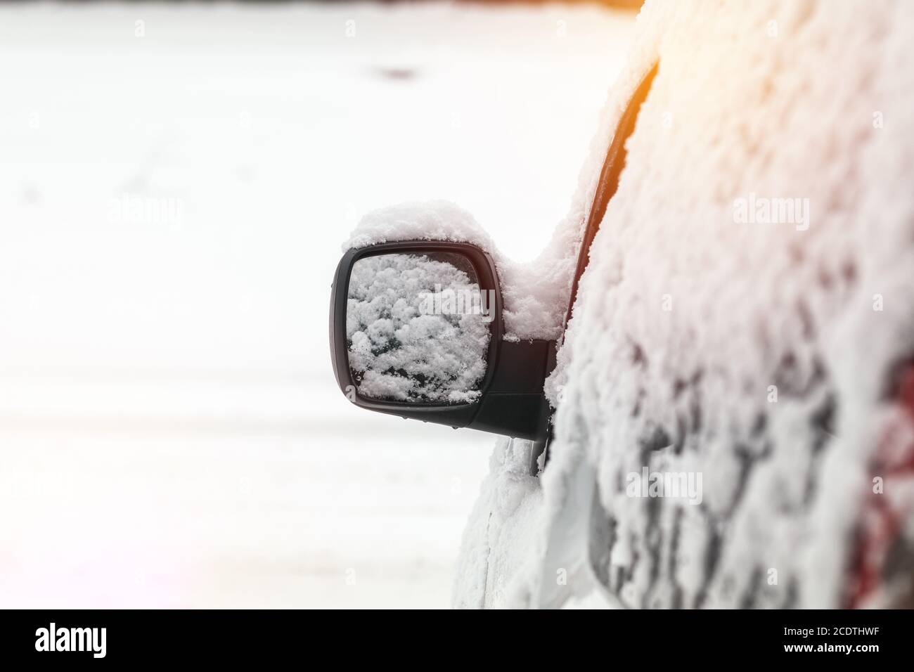 L'auto è coperta di neve. Neve sullo specchietto retrovisore. Concetto di guida in inverno con neve su strada. Foto a colori con Foto Stock