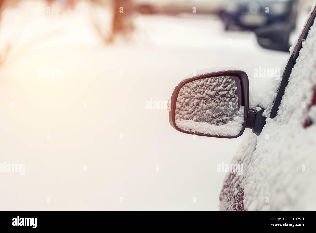 L'auto è coperta di neve. Neve sullo specchietto retrovisore. Concetto di guida in inverno con neve su strada. Foto a colori con Foto Stock