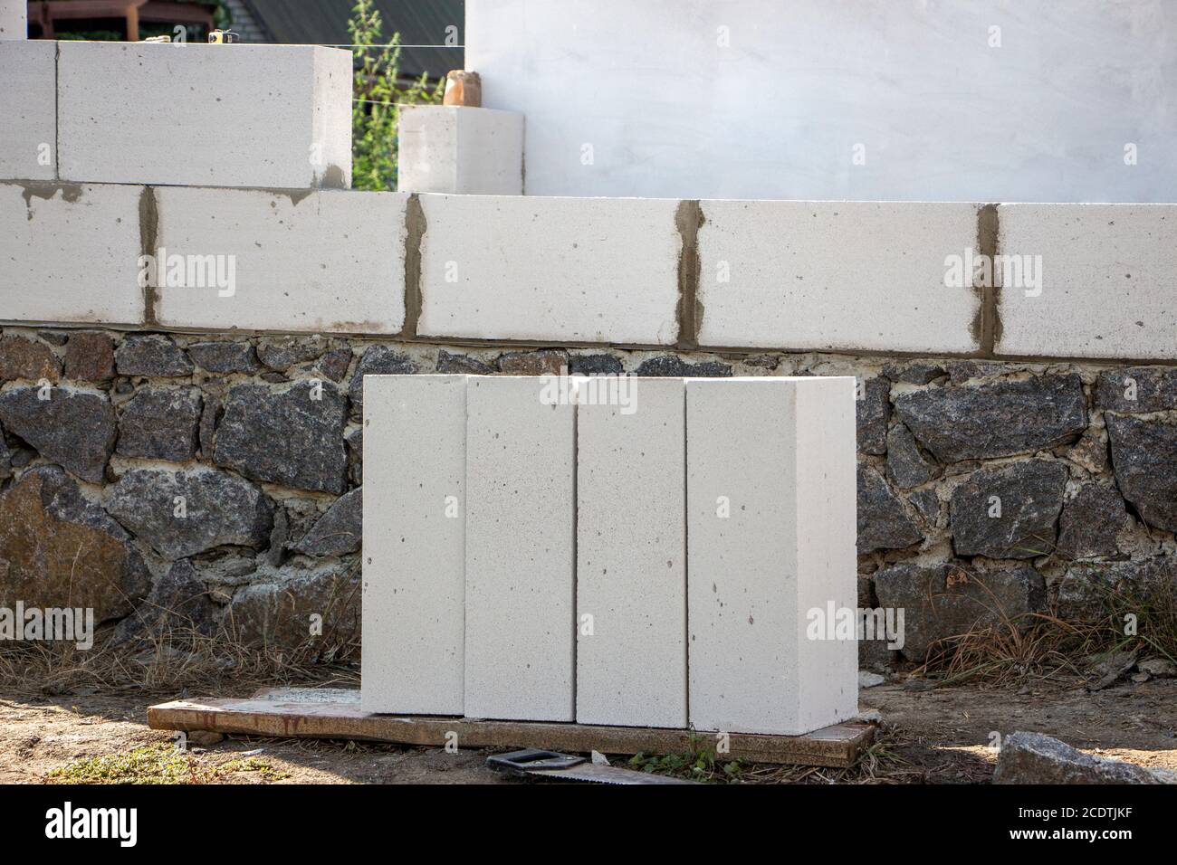 Il materiale da costruzione in calcestruzzo aerato si trova vicino alla fondazione in pietra della casa. Foto Stock