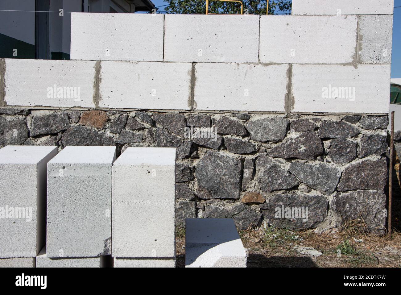 Costruzione di una casa con materiali in cemento aerato che giace vicino alla fondazione in pietra. Foto Stock