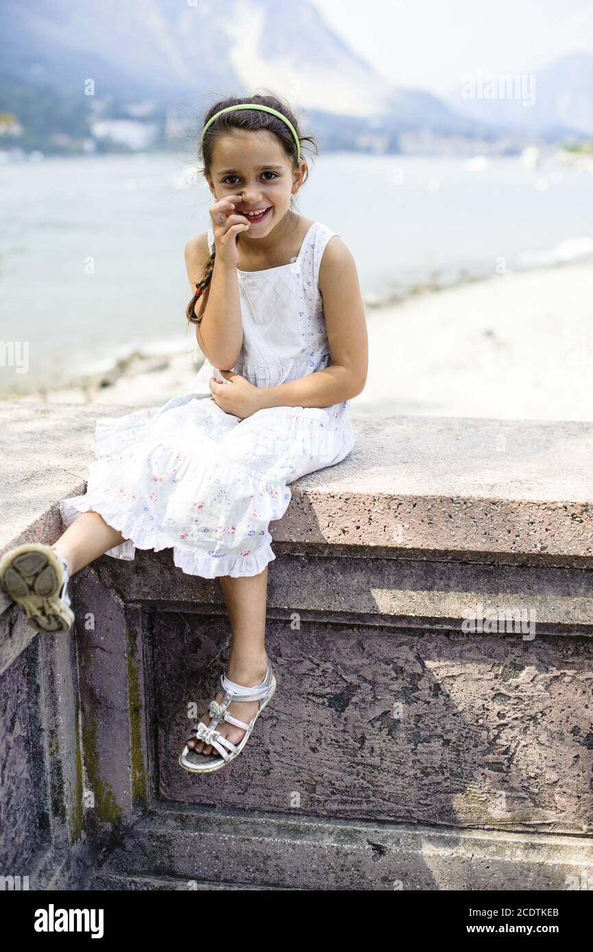 ritratto di una ragazza di 7 anni seduta su un parete Foto Stock