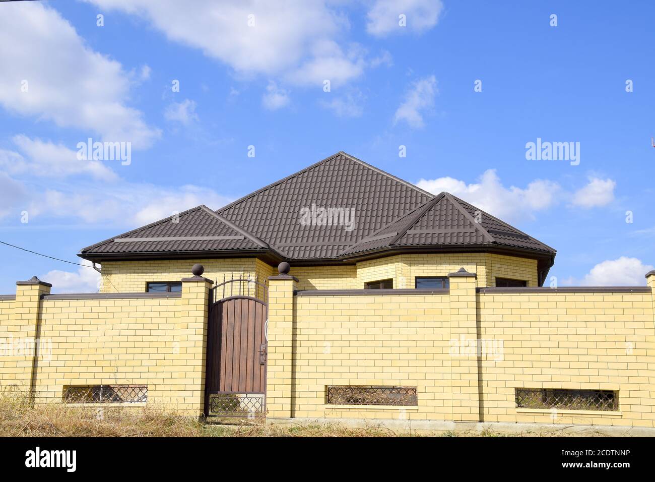 Metallo decorativo sul tetto di una casa in mattoni. Recinzione in metallo ondulato. Foto Stock