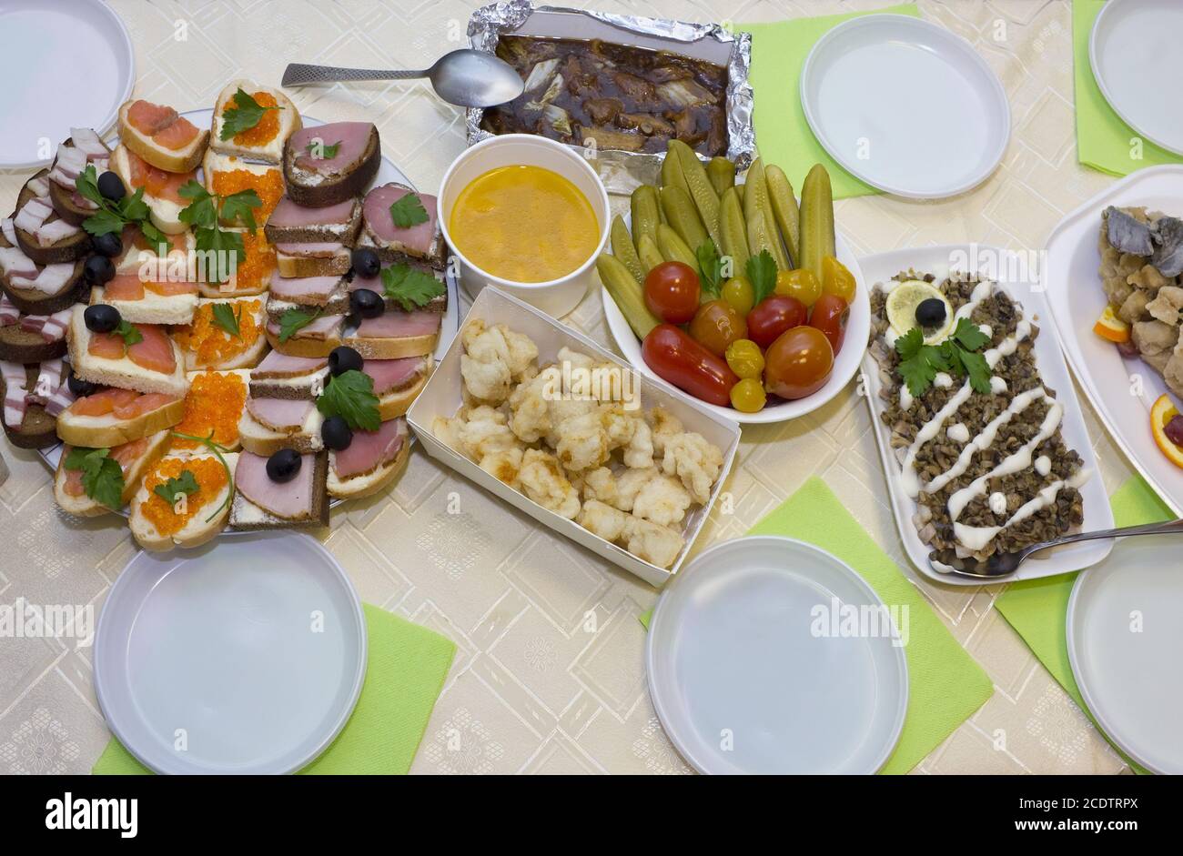 Un tavolo festivo con cibo e spuntini in una compagnia povera. Foto Stock