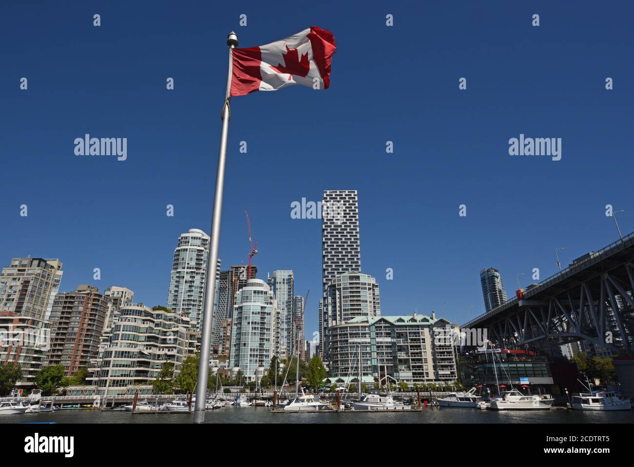 Una bandiera canadese vola di fronte agli appartamenti del centro e ai condomini sullo skyline di Vancouver, British Columbia, Canada Foto Stock