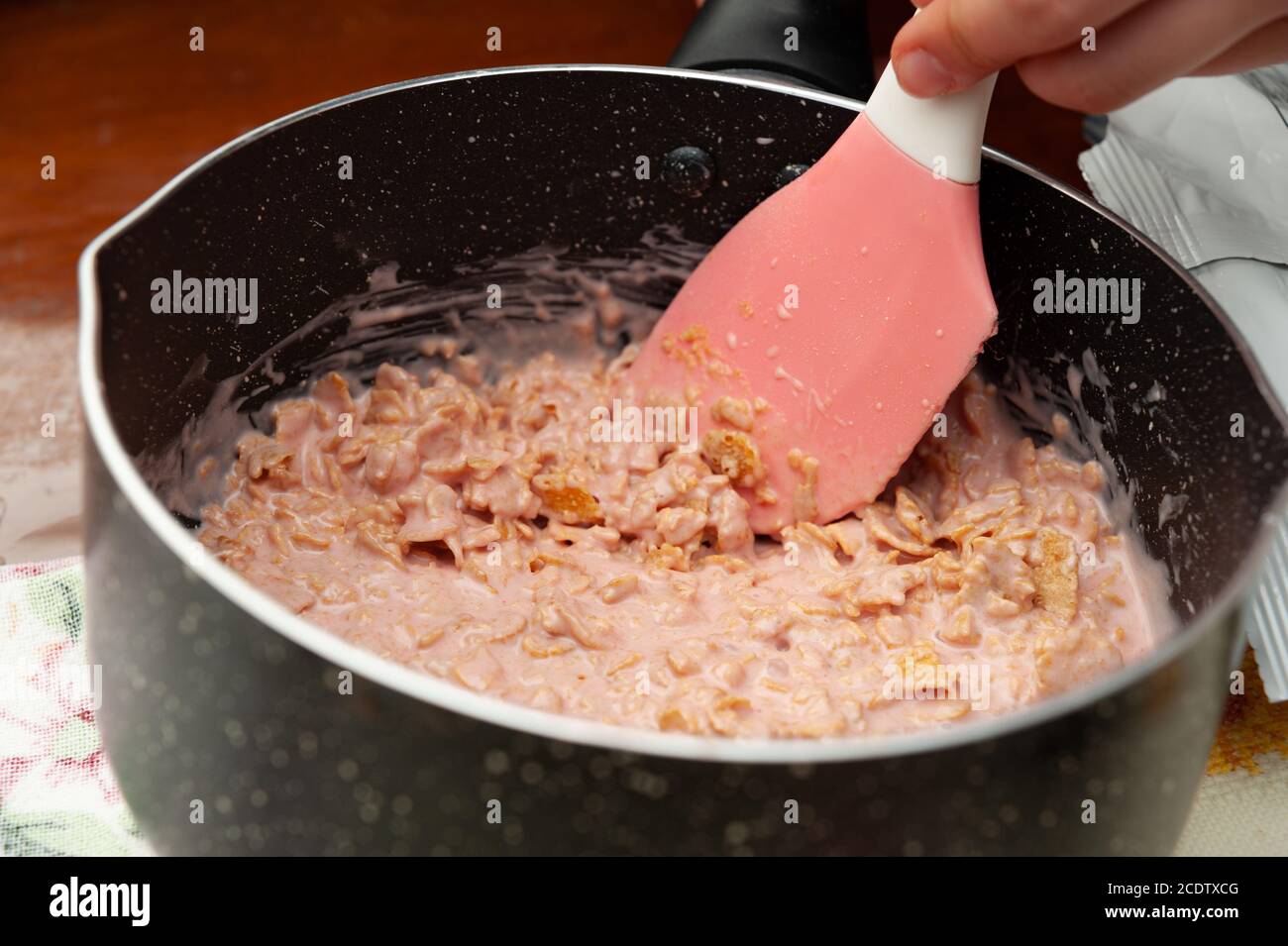 Preparare a mano i fiocchi di mais in cioccolato alla fragola fuso nella padella. Primo piano. Shot orizzontale. Foto Stock