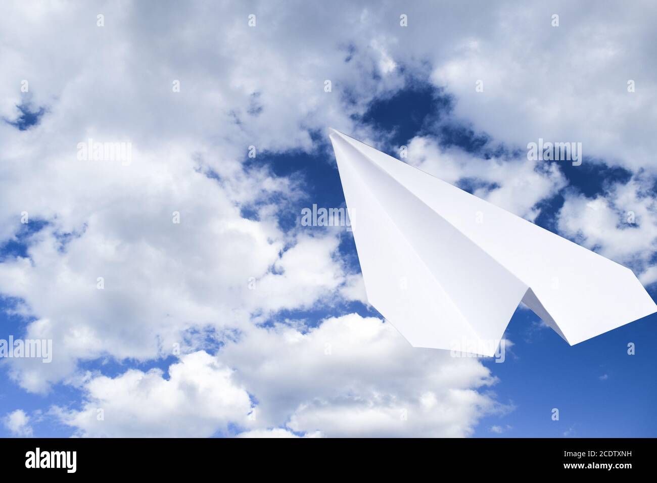 White aeroplano di carta in un cielo blu con nuvole. Il simbolo del messaggio in messenger Foto Stock