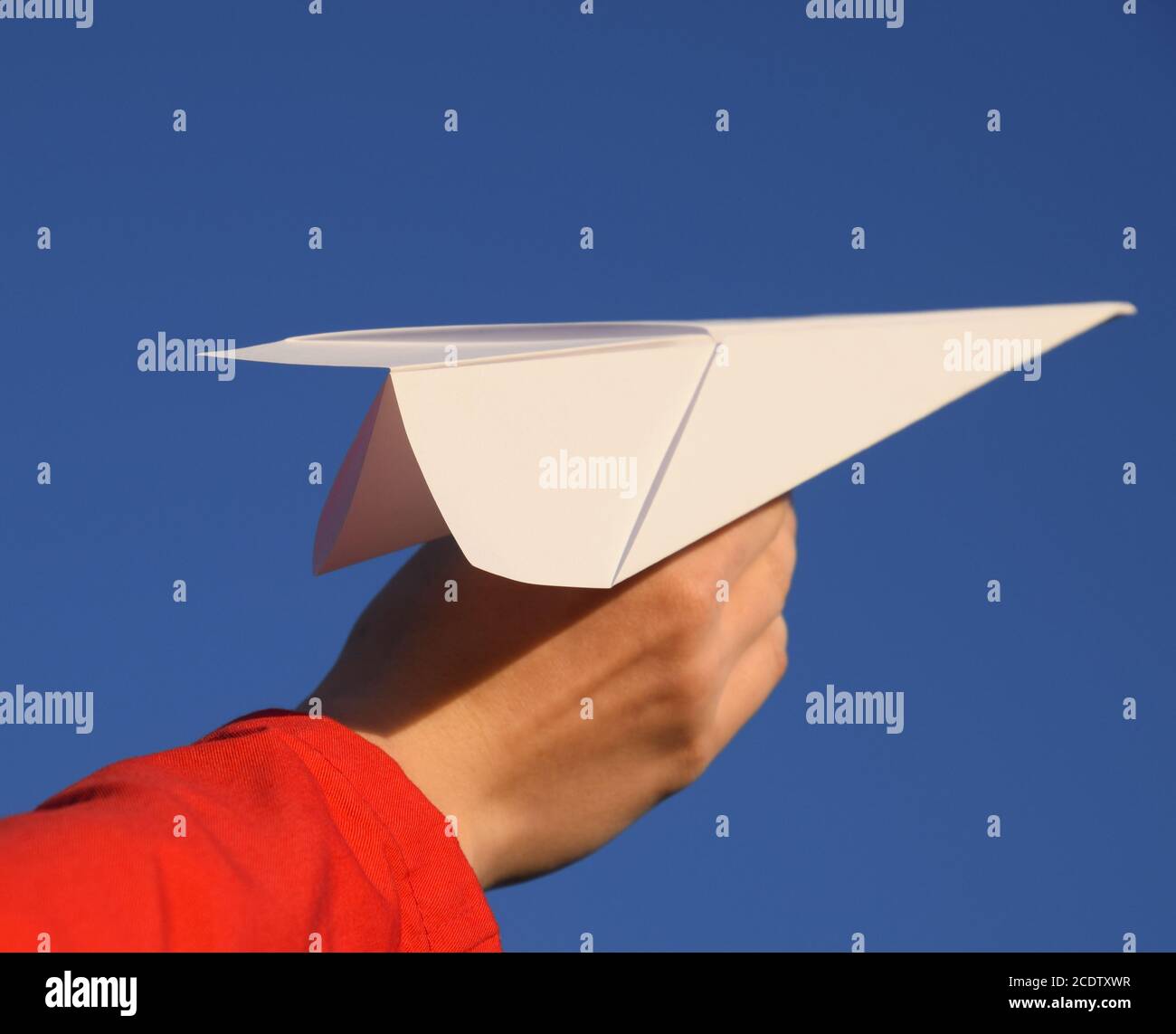 White aeroplano di carta in mano contro il cielo. Un simbolo di libertà su Internet Foto Stock