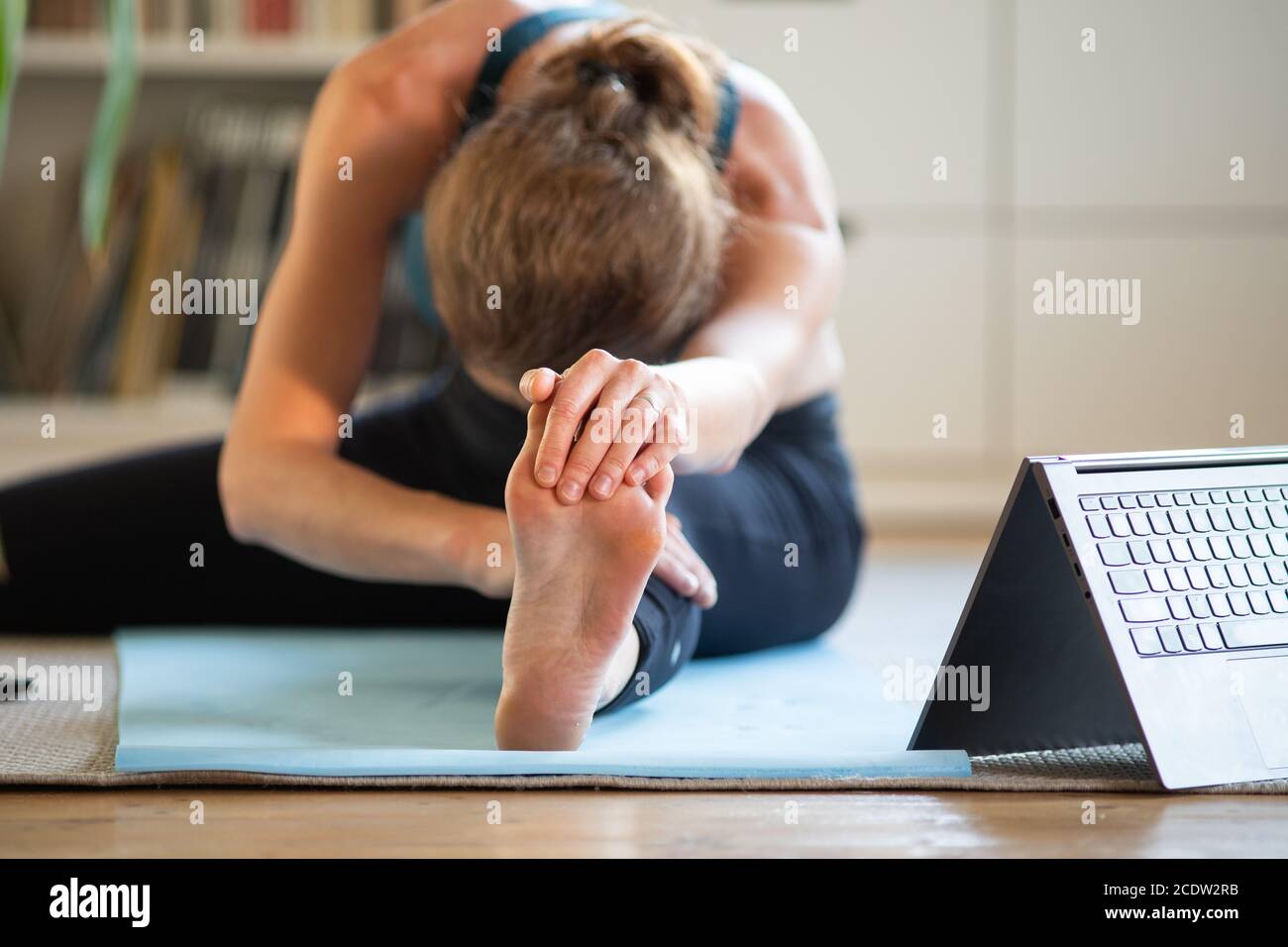 donna che fa yoga a casa guardando video online Foto Stock