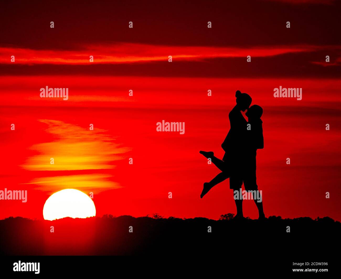 Romantica coppia in campagna al tramonto con il sole e cielo rosso Foto Stock