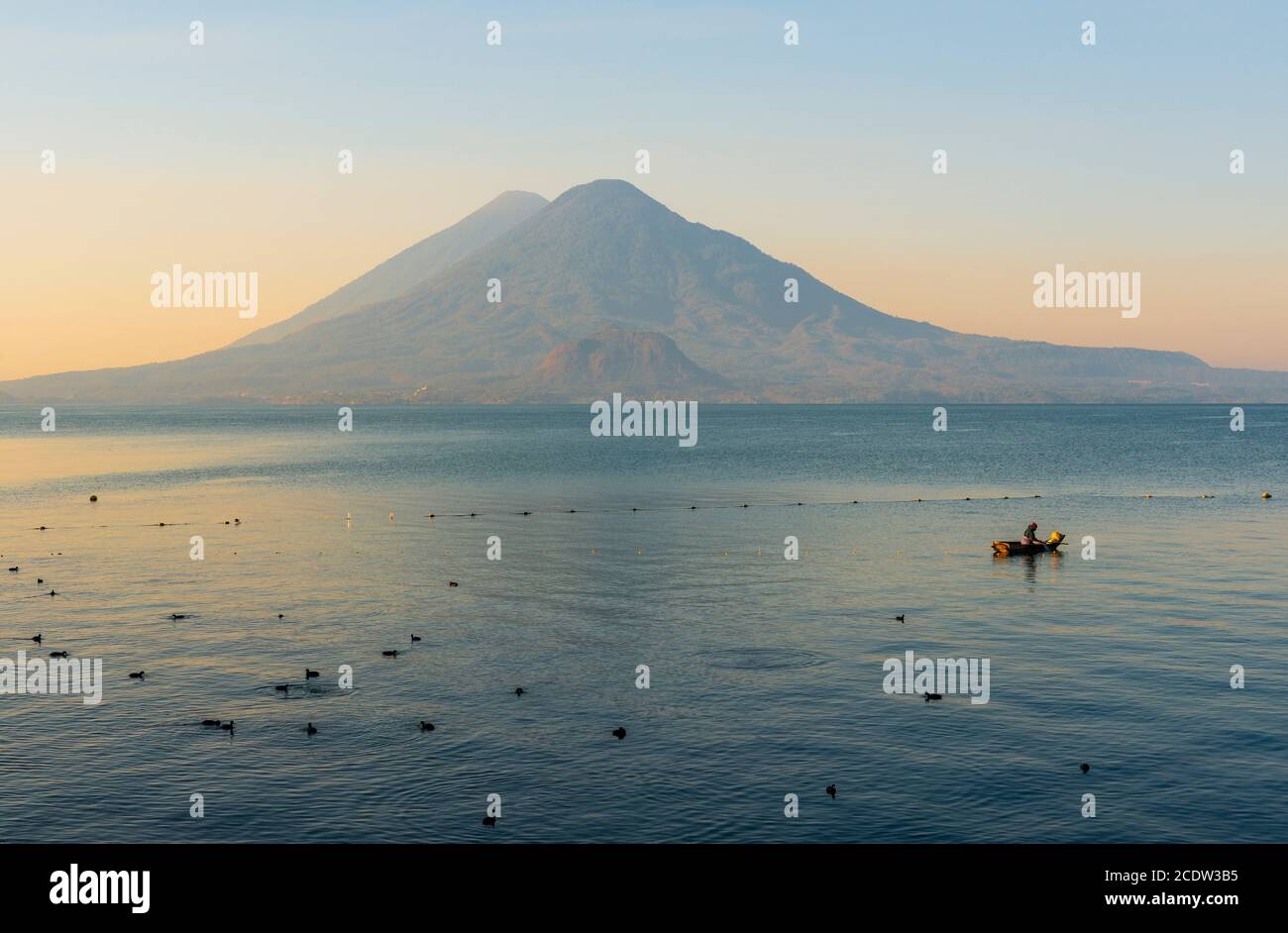 Pescatore che controlla le sue reti per i pesci nel lago Atitlan all'alba con il vulcano Toliman e Atitlan sullo sfondo, Panajachel, Guatemala. Foto Stock
