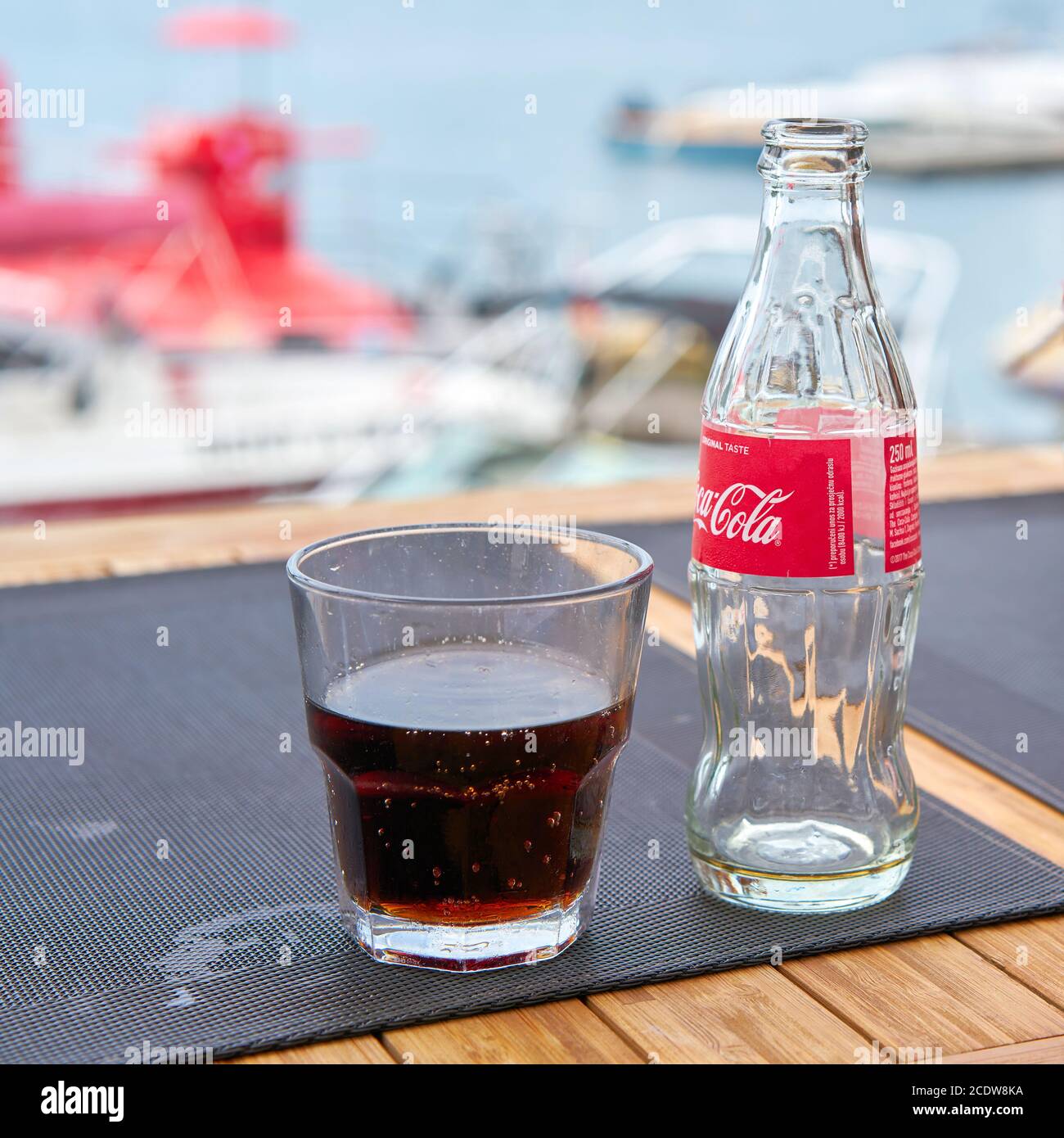 Bottiglia di Coca-Cola e un bicchiere sul tavolo di un beach bar della città Vrsar in Croazia Foto Stock