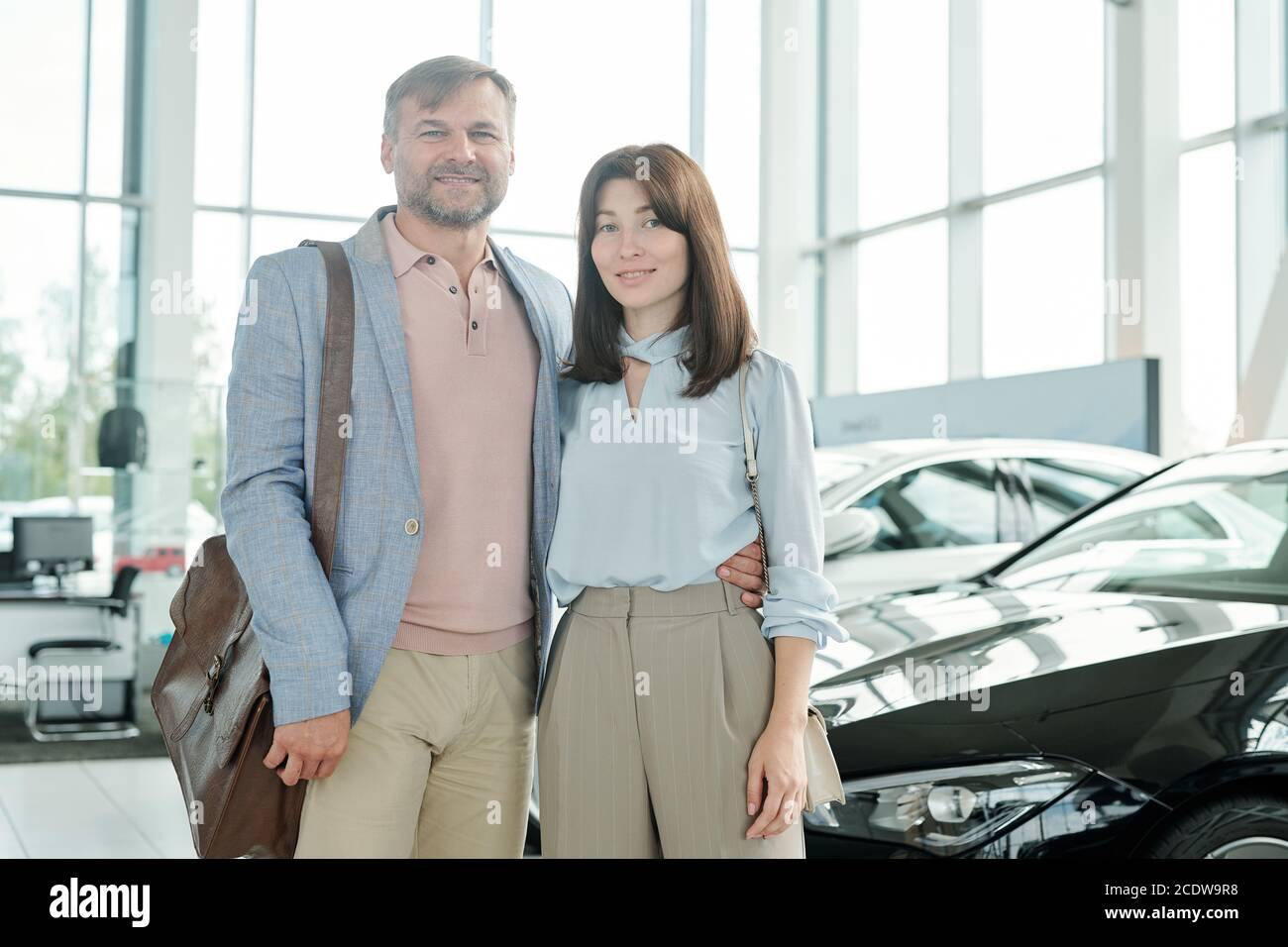 Allegra affettuosa coppia di mezza età all'interno di un grande centro auto contemporaneo Foto Stock