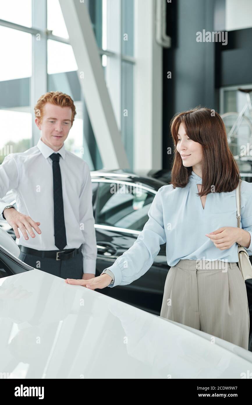 Elegante donna brunette consumatore guardando nuova auto di lusso in centro automatico Foto Stock