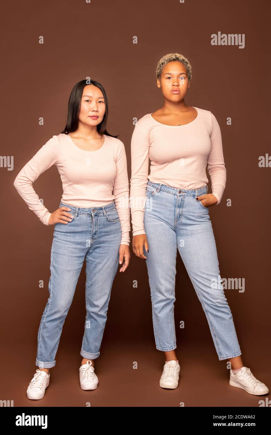 Due giovani eleganti donne di etnie africane e asiatiche abbigliamento casualwear Foto Stock