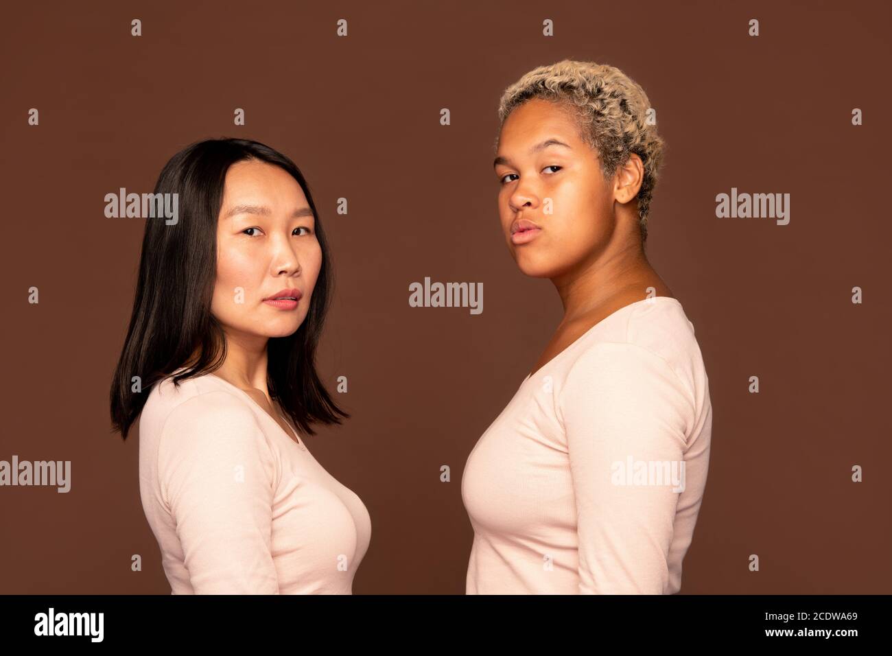 Due ragazze serie di etnie africane e asiatiche in pullover ti guarda Foto Stock