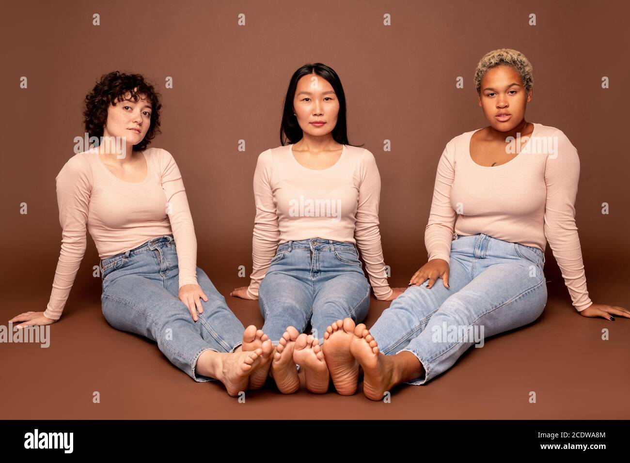 Gruppo di giovani donne contemporanee di varie etnie che si siedono il pavimento Foto Stock