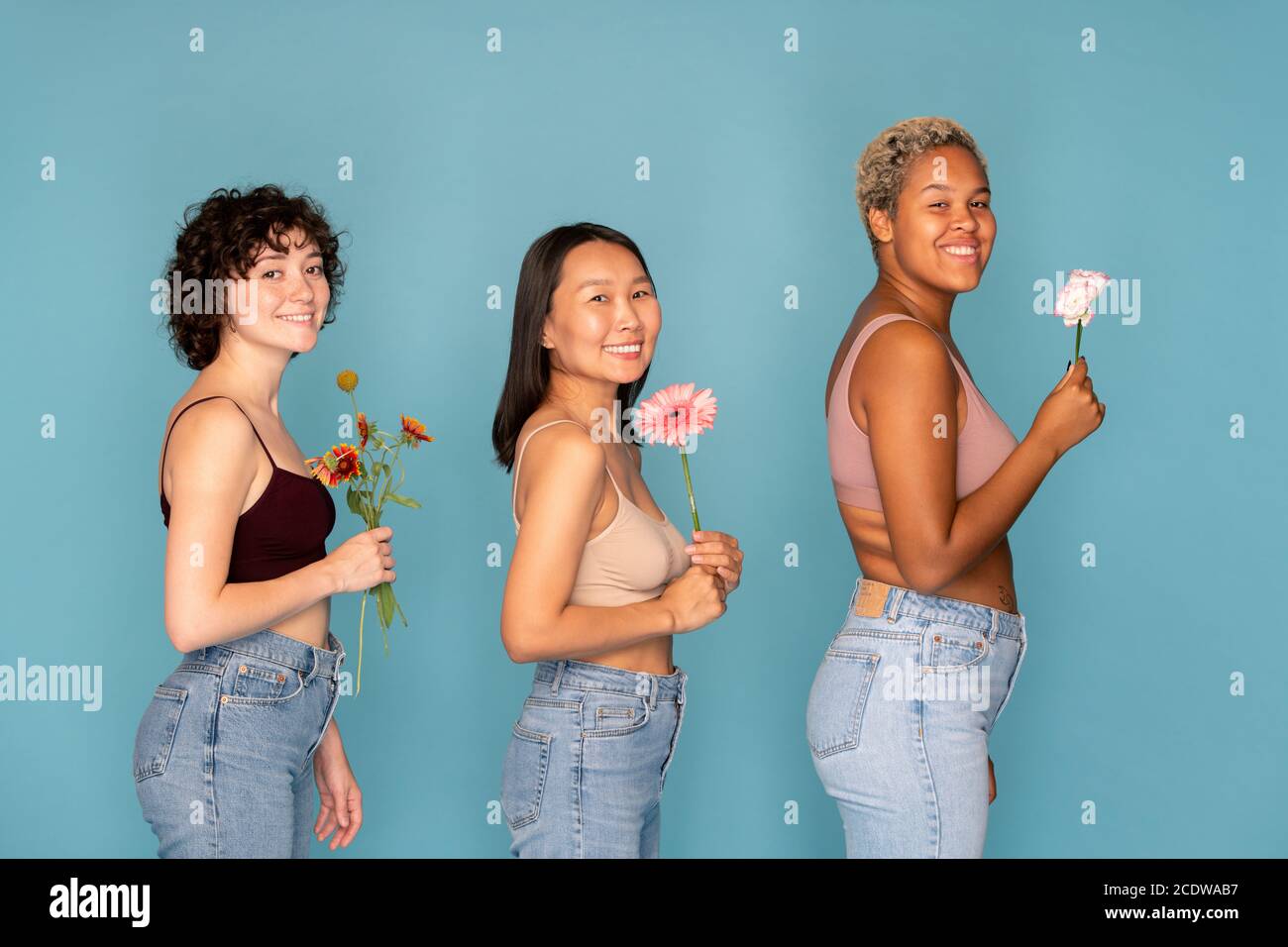 Tre giovani donne allegre in tenera e jeans blu fiori freschi Foto Stock