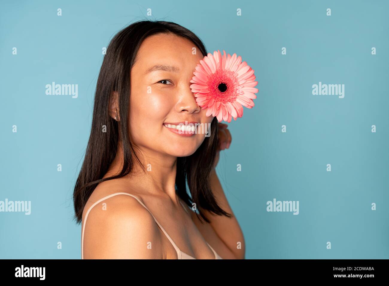 Giovane bella donna asiatica con un sorriso toothy che tiene il rosa meraviglioso erbera Foto Stock