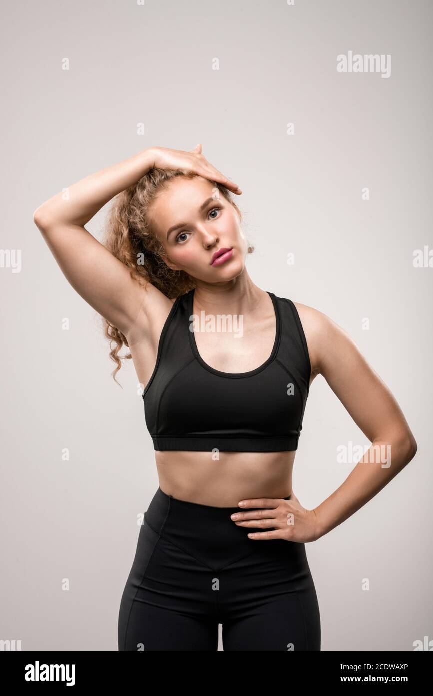 Indossa una tuta nera che tocca la sua lunga bionda capelli ricci Foto Stock