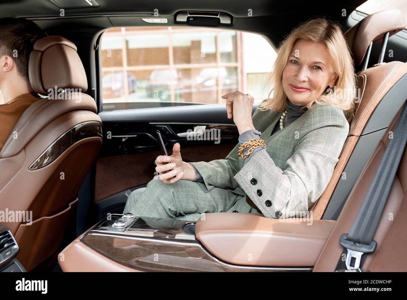 Donna d'affari di successo che usa lo smartphone e ti guarda con un sorriso Foto Stock