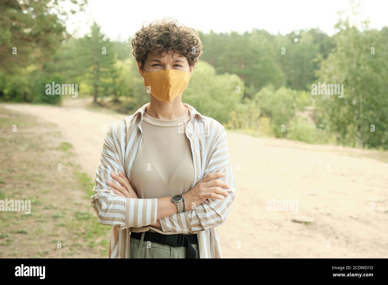 Giovane bella bruna femmina in maschera protettiva che attraversa le braccia dal petto Foto Stock