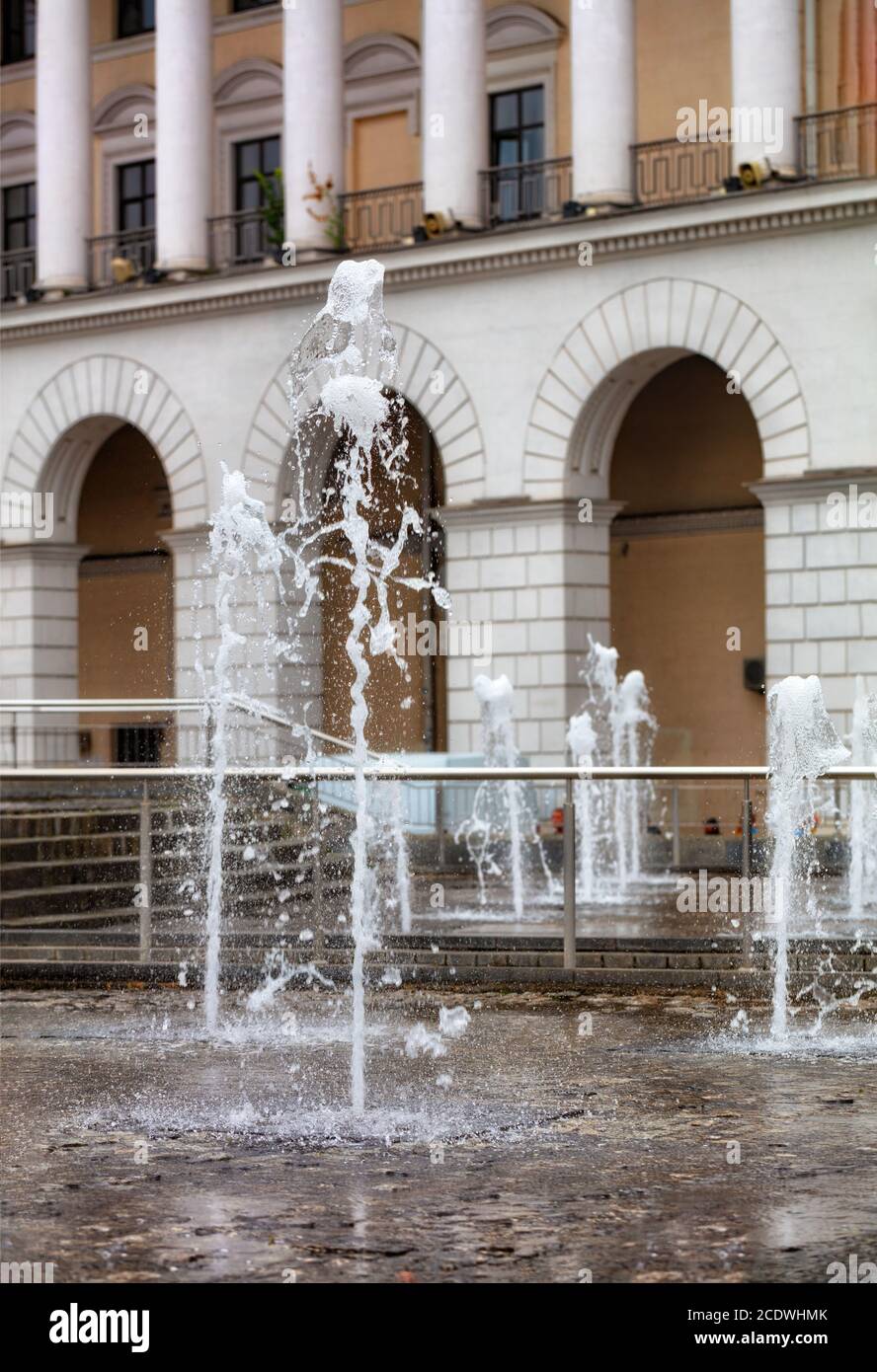 Potenti getti d'acqua si innalzano nella fontana della città sullo sfondo della facciata ad arco e a colonne del Conservatorio di Kiev. Foto Stock