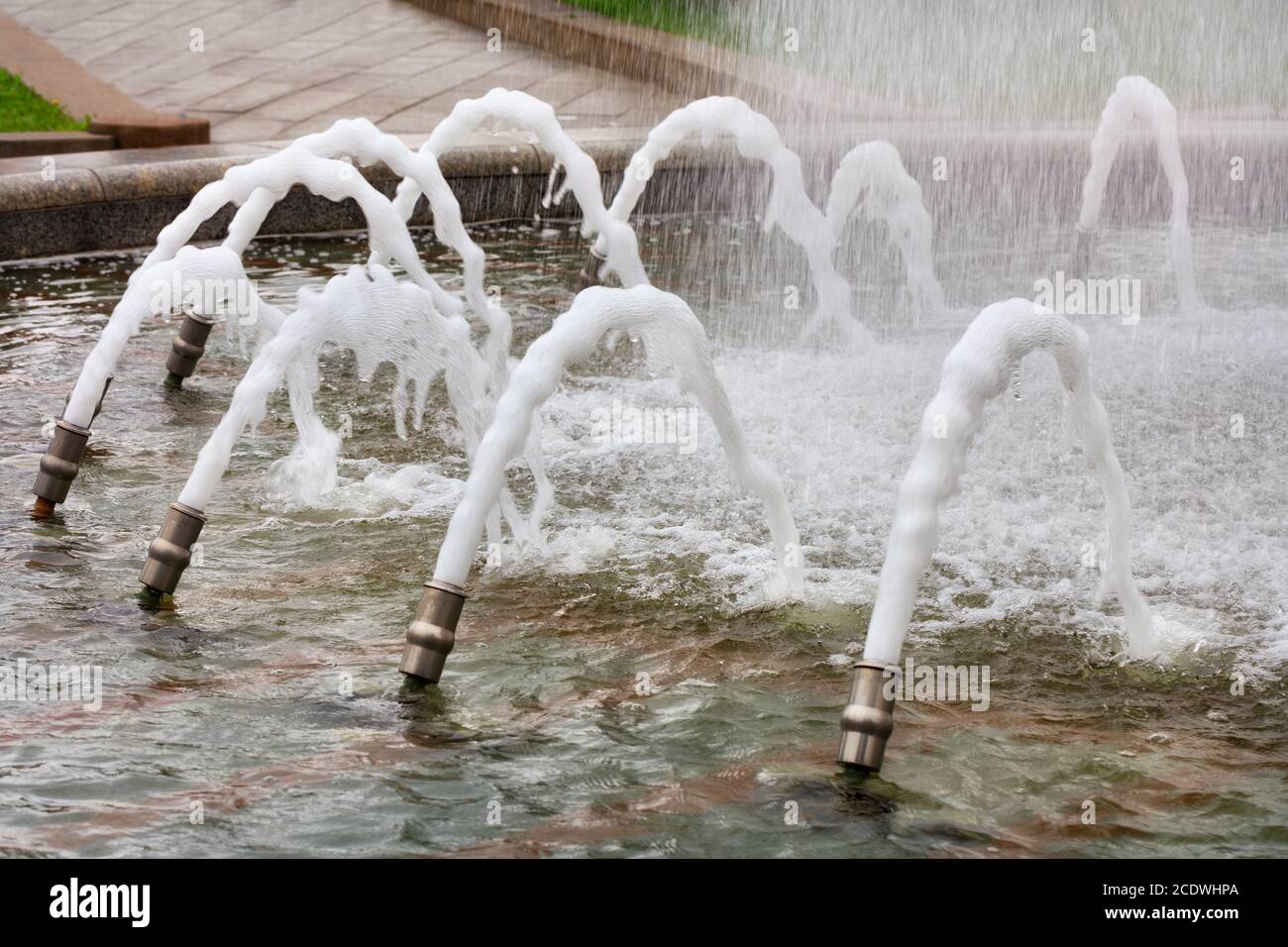 Nella fontana della città, i cannoni metallici creano una splendida giostra d'acqua con getti d'acqua schiumosi che esplodono in superficie. Foto Stock