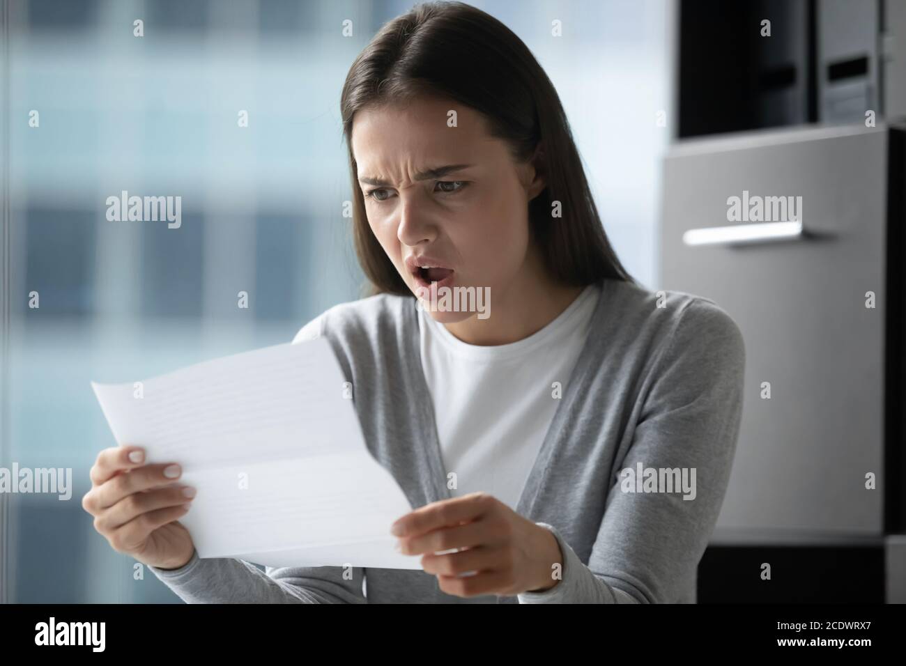 Arrabbiato infastidito giovane donna d'affari che legge la lettera, ha ricevuto le notizie difettose Foto Stock