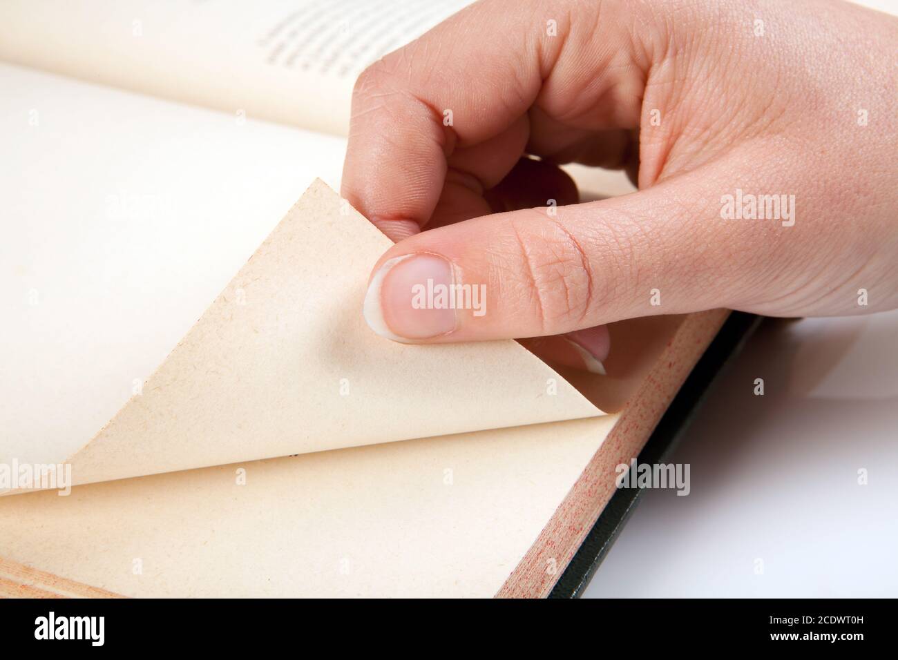 Mano femminile che gira una pagina di un vecchio libro Foto Stock