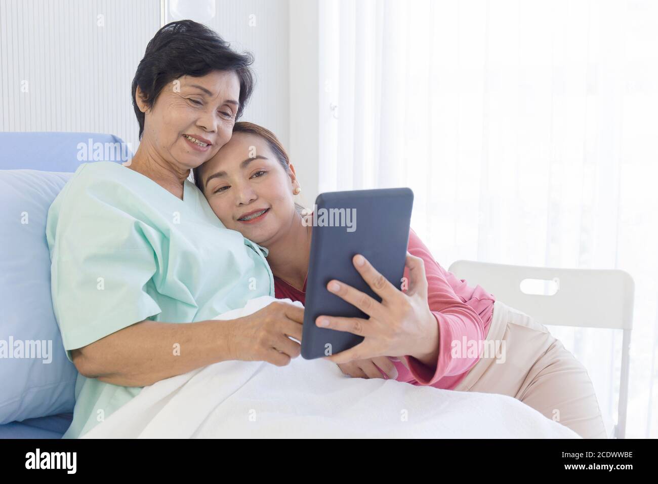 La madre malata giaceva sul letto dell'ospedale e sua figlia l'una accanto all'altra faceva videochiamate in modo felice. Foto Stock