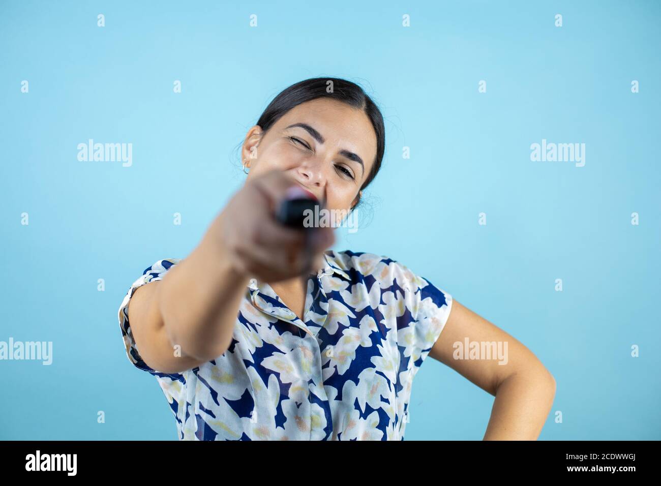 Giovane bella donna in piedi su sfondo blu insolato premendo un pulsante. Foto Stock