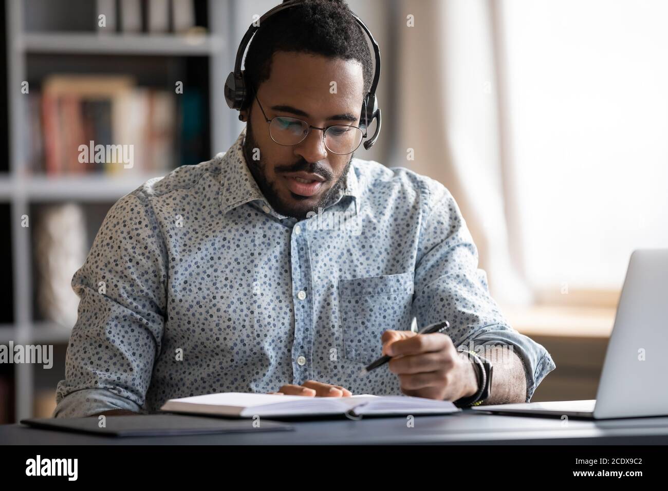 Uomo afro-americano serio messo a fuoco che indossa le note di scrittura delle cuffie Foto Stock