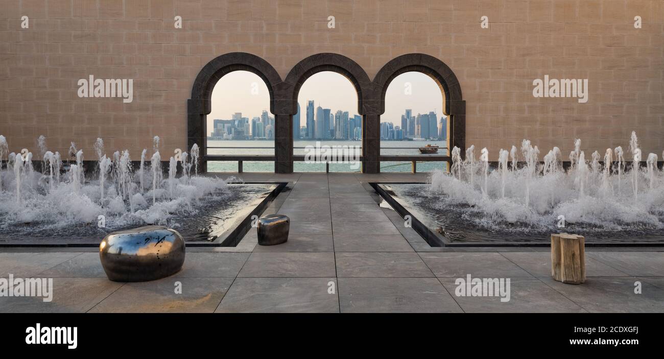 Il tramonto sullo skyline di Doha è stato girato dal Museo di Arte Islamica Con dhow nel golfo arabo e fontane in primo piano Foto Stock