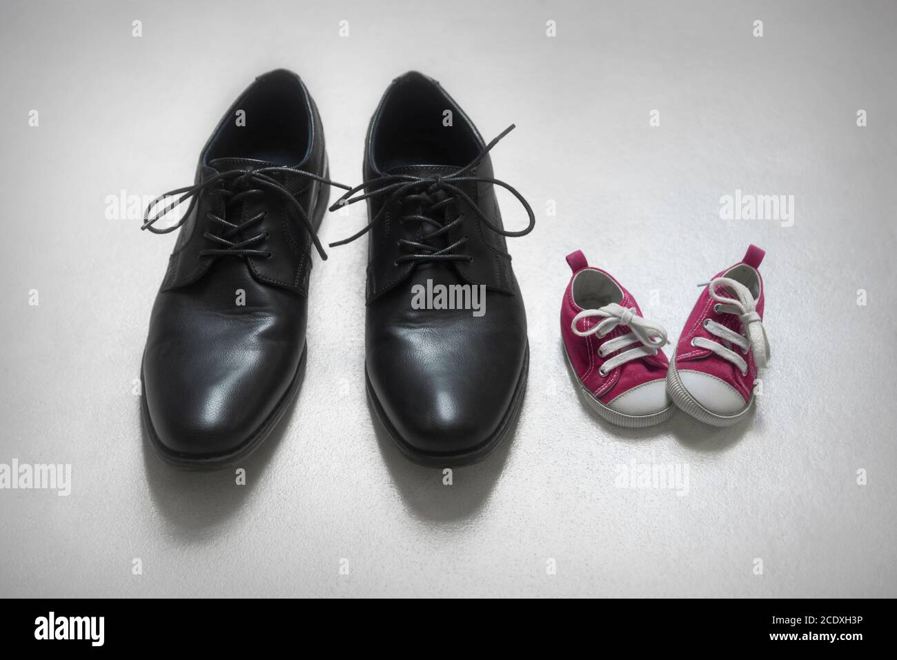 Padre con bambino metafora, bambina e scarpe per adulti. Foto Stock